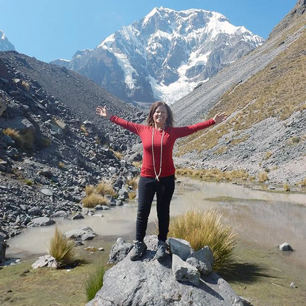 Isa Herrera in the Andes mountains of Peru, arms thrown wide against the mountainside.