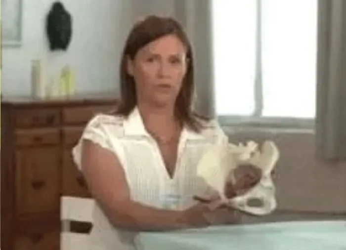 Isa Herrera holding an anatomical model of the pelvis during a filmed television segment.
