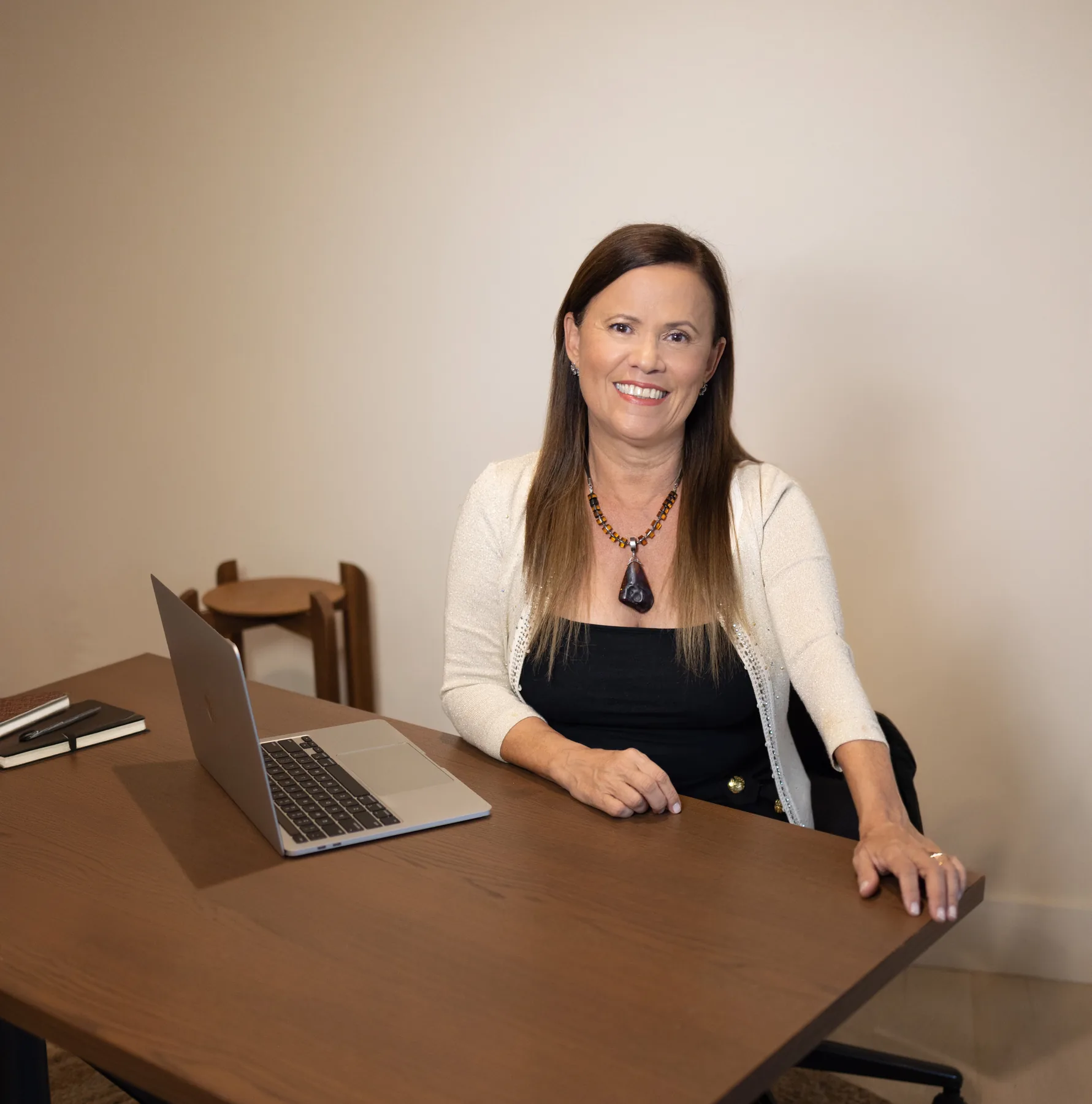 Isa Herrera in a cream cardigan seated at her desk with an open laptop.