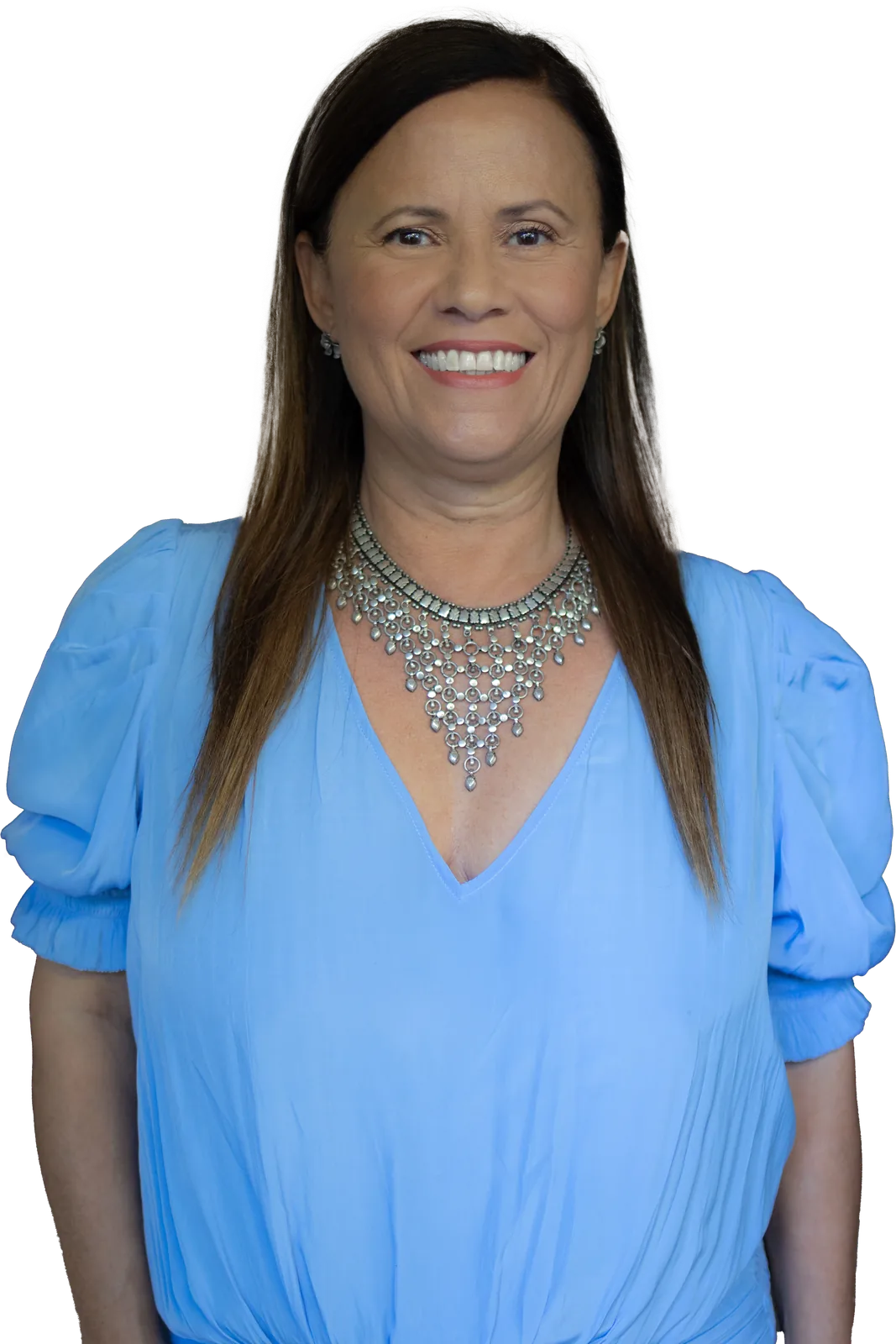 Isa Herrera in a light blue blouse and silver statement necklace, smiling at the reader.