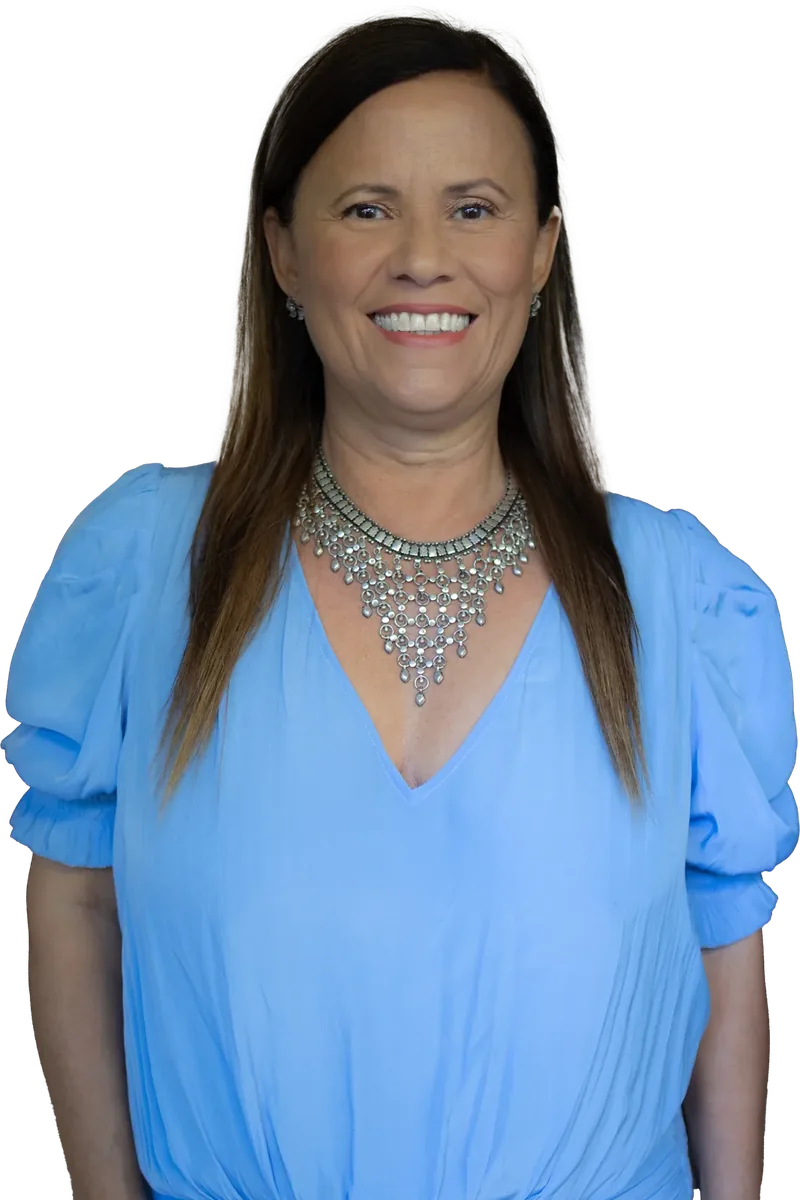 Isa Herrera in a light blue blouse and silver statement necklace, smiling at the reader.